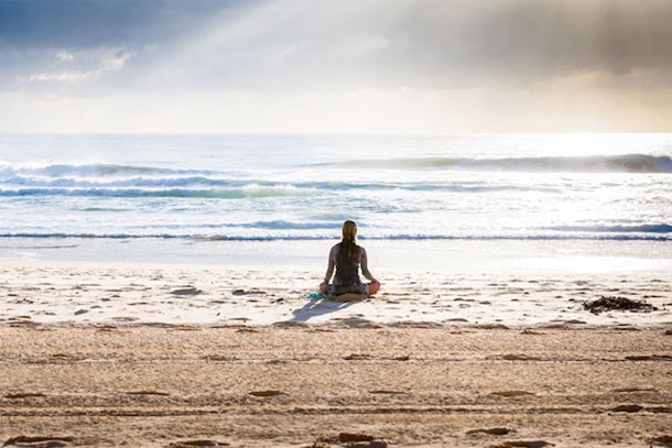 women meditating on beach with tranquil ambiance to reach calm mental state